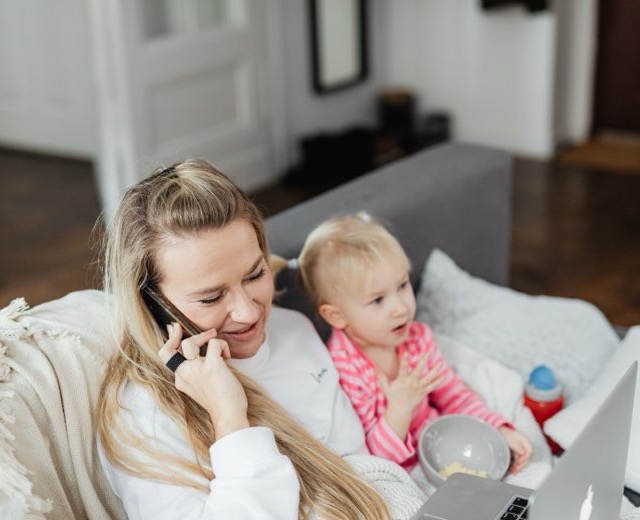 A parent on the phone with a toddler on their lap