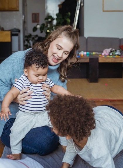 Au pair playing on the floor with two small children