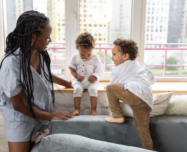 Au pair playing with two toddlers on a sofa