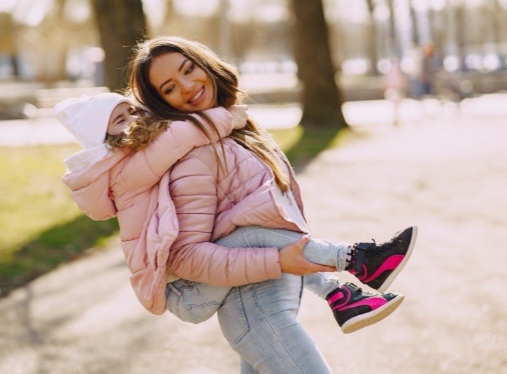 Au pair carrying a child on their back in a park