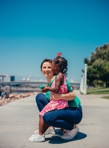 Au pair hugging a child outdoors